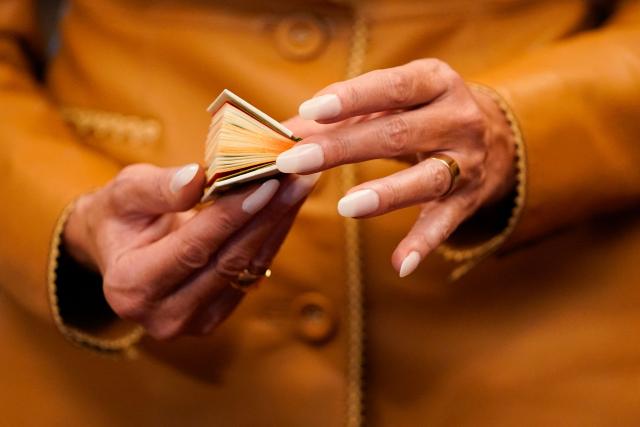 US First Lady Melania Trump holds a miniature antique book as she tours the Royal Library at Windsor Castle, in Windsor, on September 18, 2025, on the second day of a second State Visit. US President Donald Trump and his wife Melania were treated to a sumptuous royal state banquet in Windsor Castle Wednesday, rounding off the US president's first full day of a historic second state visit to Britain. (Photo by Nathan Howard / POOL / AFP)