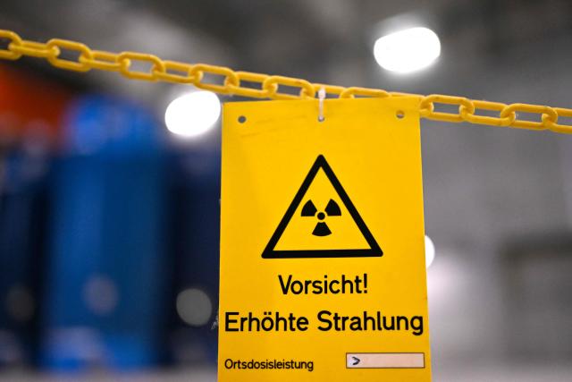A photo shows a sign 'Caution! Increased radiation' in front of Castor containers for highly radioactive fuel elements from the former Gundremmingen and Neckarwestheim nuclear power plants at the Ahaus interim storage facility in Ahaus, western Germany on September 18, 2025. On August 26, 2025, the Federal Office for the Safety of Nuclear Waste Disposal (BASE) approved the controversial transport of nuclear waste from Juelich in the Rhineland to the interim storage facility in Ahaus in the Muensterland region. (Photo by Ina FASSBENDER / AFP)