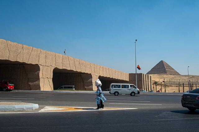 A woman walks on a road near the Grand Egyptian Museum toward the Giza Pyramids necropolis on the southwestern outskirts of the Egyptian capital Cairo on September 18, 2025. (Photo by Khaled DESOUKI / AFP)