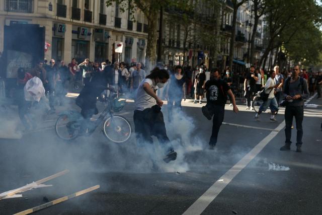 A protestor throws back tear gas canister in Paris on September 18, 2025, during a day of nationwide strikes and protests called by unions over France's national budget. France is bracing for a day of nationwide protests on September 18, 2025, with a source close to the authorities saying some 800,000 people are expected to take to the streets. In a rare show of unity, trade unions have urged French people to strike in protest at the authorities' "horror show" draft budget designed to reduce France's ballooning debt. (Photo by Alain JOCARD / AFP)