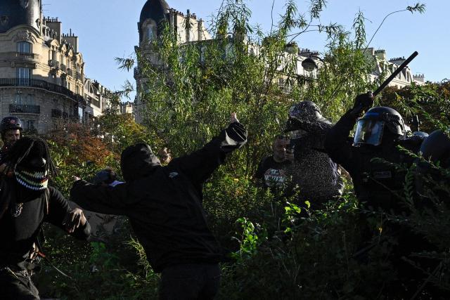 A French police officer uses a baton to disperse protestors in Paris on September 18, 2025, during a day of nationwide strikes and protests called by unions over France's national budget. France is bracing for a day of nationwide protests on September 18, 2025, with a source close to the authorities saying some 800,000 people are expected to take to the streets. In a rare show of unity, trade unions have urged French people to strike in protest at the authorities' "horror show" draft budget designed to reduce France's ballooning debt. (Photo by JULIEN DE ROSA / AFP)