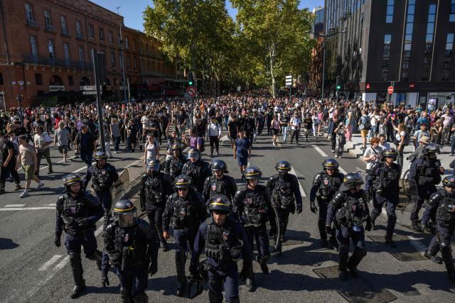 Demonstrators march behind French Republican Security Corps (CRS - Compagnies Republicaines de Securite) police officers during a protest entitled 'Bloquons Tout' in Toulouse, southwestern France, on September 18, 2025, during a day of nationwide strikes and protests called by unions over France's national budget. France is bracing for a day of nationwide protests on September 18, 2025, with a source close to the authorities saying some 800,000 people are expected to take to the streets. In a rare show of unity, trade unions have urged French people to strike in protest at the authorities' "horror show" draft budget designed to reduce France's ballooning debt. (Photo by Ed JONES / AFP)