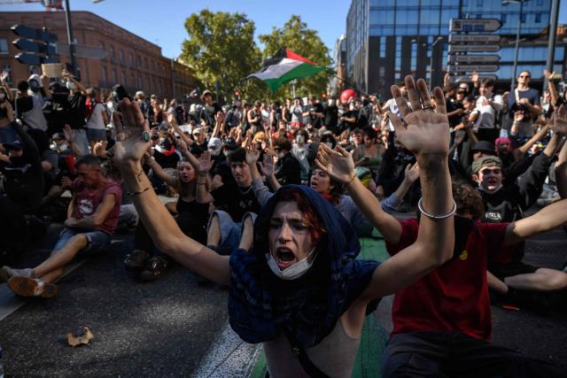 TOPSHOT - Demonstrators shout slogans as they sit before a police cordon during a protest entitled 'Bloquons Tout' in Toulouse, southwestern France, on September 18, 2025, during a day of nationwide strikes and protests called by unions over France's national budget. France is bracing for a day of nationwide protests on September 18, 2025, with a source close to the authorities saying some 800,000 people are expected to take to the streets. In a rare show of unity, trade unions have urged French people to strike in protest at the authorities' "horror show" draft budget designed to reduce France's ballooning debt. (Photo by Ed JONES / AFP)