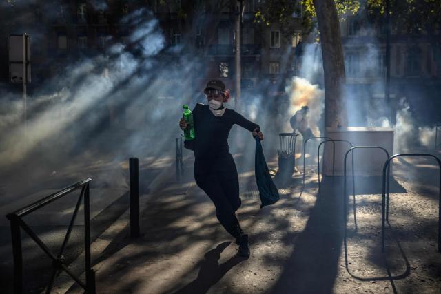 A demonstrator runs away from tear gas after clashing with police during a protest entitled 'Bloquons Tout' in Toulouse, southwestern France, on September 18, 2025, during a day of nationwide strikes and protests called by unions over France's national budget. France is bracing for a day of nationwide protests on September 18, 2025, with a source close to the authorities saying some 800,000 people are expected to take to the streets. In a rare show of unity, trade unions have urged French people to strike in protest at the authorities' "horror show" draft budget designed to reduce France's ballooning debt. (Photo by Ed JONES / AFP)