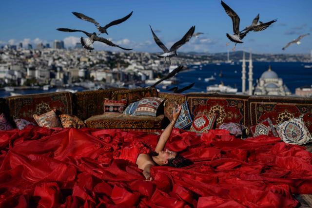 A tourist poses for a photograph in an open-air studio terrace, in Istanbul on September 18, 2025. (Photo by Yasin AKGUL / AFP)