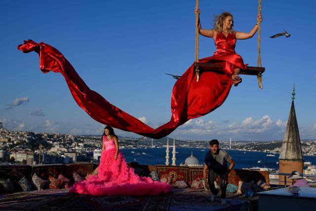Tourists looks out towards the Bosphorus as they pose for a photograph in an open-air studio terrace, in Istanbul on September 18, 2025. (Photo by Yasin AKGUL / AFP)