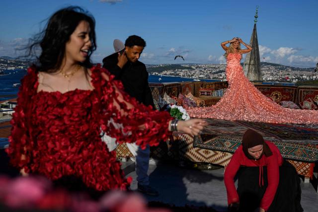 Tourists looks out towards the Bosphorus as they pose for a photograph in an open-air studio terrace, in Istanbul, on September 18, 2025. (Photo by Yasin AKGUL / AFP)