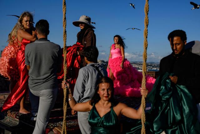 Tourists look out towards the Bosphorus as they pose for a photograph in an open-air studio terrace, in Istanbul on September 18, 2025. (Photo by Yasin AKGUL / AFP)