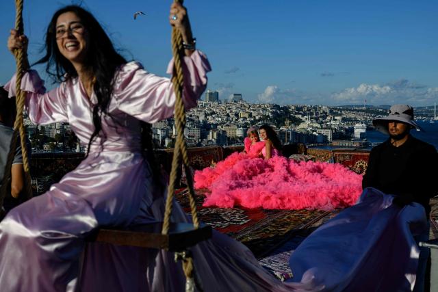 Tourists look out towards the Bosphorus as they pose for a photograph in an open-air studio terrace, in Istanbul on September 18, 2025. (Photo by Yasin AKGUL / AFP)