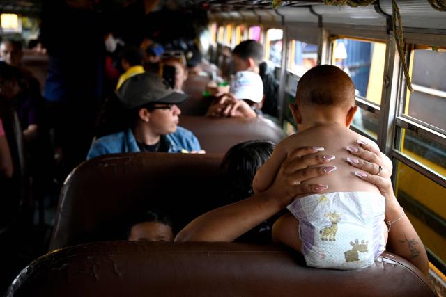 A woman holds a baby over a seat inside a bus at the Zona Belen market in Tegucigalpa on September 18, 2025. (Photo by Orlando SIERRA / AFP)