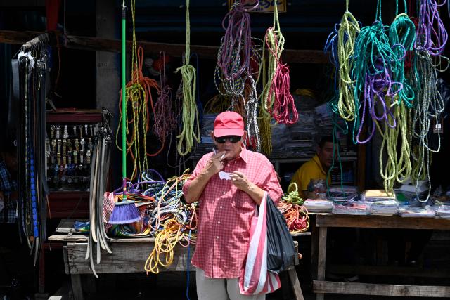 A man smokes a cigarette in front of a rope shop at the Zona Belen market in Tegucigalpa on September 18, 2025. (Photo by Orlando SIERRA / AFP)