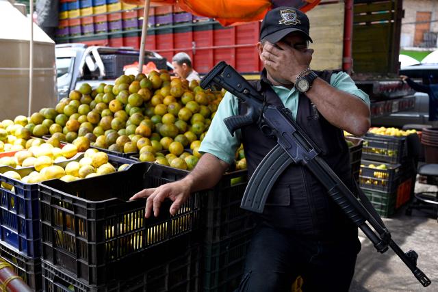 A private security guard gestures in front of an orange stand at the Zona Belen market in Tegucigalpa on September 18, 2025. (Photo by Orlando SIERRA / AFP)