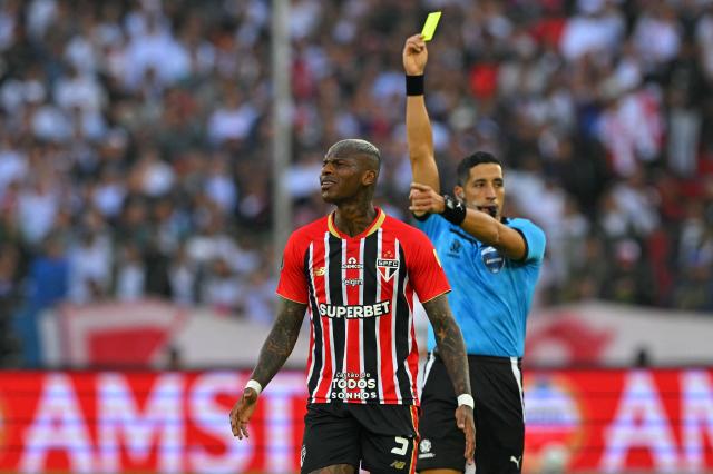 Argentine referee Yael Falcon shows a yellow card to Sao Paulo's Ecuadorean defender #05 Robert Arboleda during the Copa Libertadores quarterfinal first leg football match between Ecuador's Liga de Quito and Brazil's Sao Paulo at the Rodrigo Paz Delgado Stadium in Quito on September 18, 2025. (Photo by Rodrigo BUENDIA / AFP)