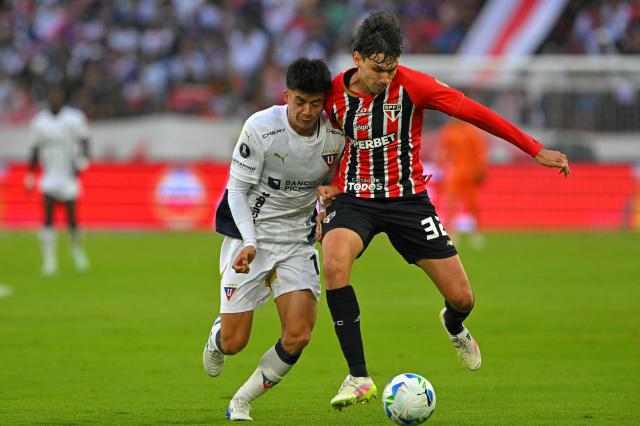 Liga de Quito's Bolivian midfielder #15 Gabriel Villamil and Sao Paulo's Venezuelan defender #32 Nahuel Ferraresi fight for the ball during the Copa Libertadores quarterfinal first leg football match between Ecuador's Liga de Quito and Brazil's Sao Paulo at the Rodrigo Paz Delgado Stadium in Quito on September 18, 2025. (Photo by Rodrigo BUENDIA / AFP)