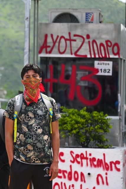 A person takes part in a protest over the 11th anniversary of the disappearance of 43 students from Ayotzinapa, at a toll road at the outskirts of Chilpancingo, Guerrero state, Mexico, on September 18, 2025. The case of the 43 students who disappeared from a rural school in Ayotzinapa in 2014 is one of the most serious human rights violations committed in Mexico, probably involving police officers, drug traffickers and military commanders, according to investigations. (Photo by Francisco ROBLES / AFP)