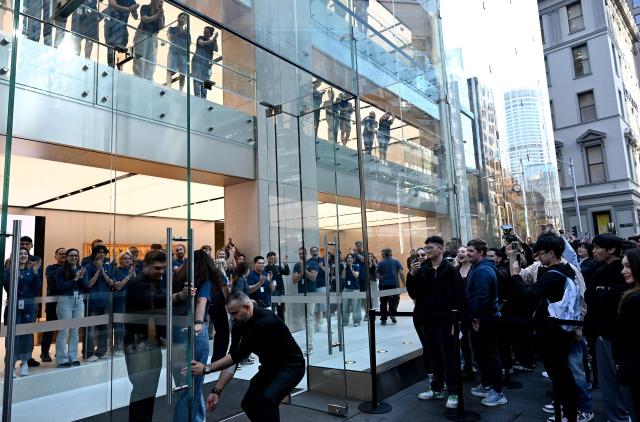 Staff open the main doors of the Apple Store in Sydney as customers arrive to collect their pre-ordered iPhone 17 Pro on September 19, 2025. (Photo by Saeed KHAN / AFP)