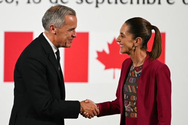 Canada's Prime Minister Mark Carney (L) and Mexico's President Claudia Sheinbaum (R) shake hands during a joint press conference at the National Palace in Mexico City on September 18, 2025. Mexico's President Claudia Sheinbaum and Canada's Prime Minister Mark Carney met in Mexico City as Trump pushes to renegotiate the USMCA North American trade pact in place since 2020. It replaced the NAFTA accord signed in the 1990s. (Photo by Yuri CORTEZ / AFP)