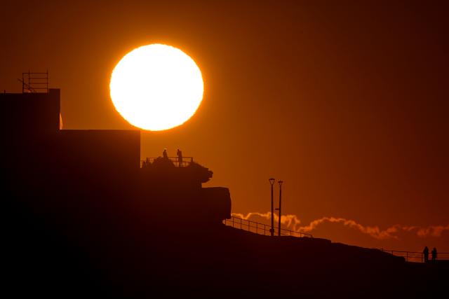 People watch the sunrise from their balcony overlooking Bondi Beach in Sydney on September 19, 2025. (Photo by Saeed KHAN / AFP)