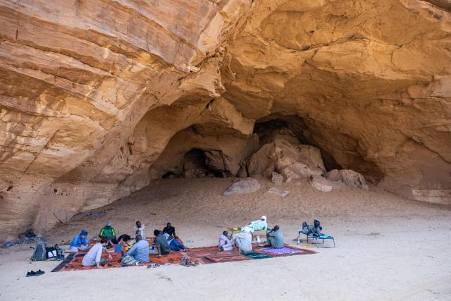 The scientific mission team rests in the shade of a cellar at the Garoa Hallagana rock art site, in Ennedi Ouest province, Chad, on July 10, 2025. A five-day scientific mission, conducted at the end of July, thirty kilometers from Fada, brought together Chadian archaeologists and geologists from the universities of N'Djamena and Abeche.
The objective: to lay "the first milestone" in the chronological markers of the ancient occupation of the Ennedi region, the researcher asserts.
The Ennedi Natural and Cultural Reserve (RNCE), created in 2018 in this Chadian province, at the crossroads with Libya and Sudan, is home to a rich archaeological heritage.
Across a sanctuary spanning more than 50,000 square kilometers, tens of thousands of rock engravings and paintings adorn the rock faces.
Following the inscription of the RNCE on the World Heritage List in 2016, the Chadian government entrusted its co-management to the South African NGO African Parks for fifteen years. (Photo by Joris Bolomey / AFP)