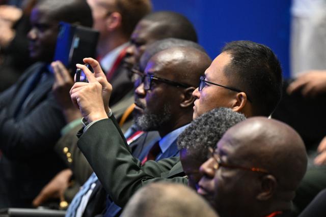 A delegate takes photos during a plenary session of the Xiangshan Forum in Beijing on September 19, 2025. (Photo by GREG BAKER / AFP)