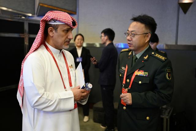A Saudi Arabian delegate chats with a Chinese delegate during a plenary session of the Xiangshan Forum in Beijing on September 19, 2025. (Photo by GREG BAKER / AFP)