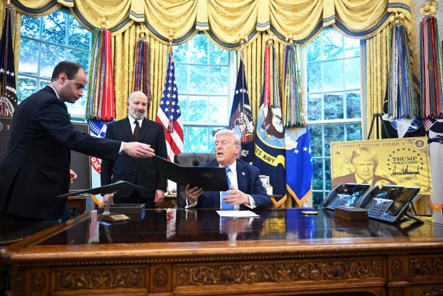 White House Staff Secretary Will Scharf (L) hands an executive order to US President Donald Trump to sign in the Oval Office of the White House in Washington, DC, on September 19, 2025 as Commerce Secretary Howard Lutnick looks on. US President Donald Trump on Friday signed an executive order creating a "gold card" residency progam for a fee of $1 million for individuals and $2 million for sponsorships by corporations. "I think it's going to be tremendously successful," Trump told journalists. (Photo by Mandel NGAN / AFP)