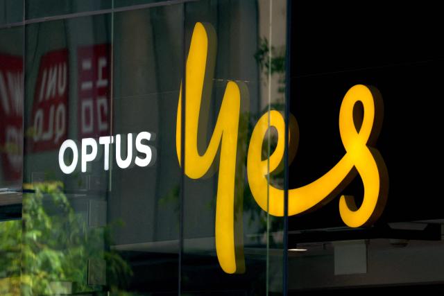 (FILES) This file photo taken on November 9, 2023 shows an illuminated sign displayed in the window of an outlet for the Australian communications company Optus in Sydney. The Australian government said September 20, 2025 that telco firm Optus "let Australians down" after three people died during a network outage that prevented calls to emergency services. (Photo by David GRAY / AFP)