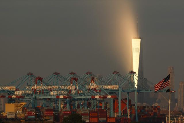 Cargo ships and shipping containers are seen at the Port Jersey Container Terminal, with the Manhattan skyline and the One World Trade Center (also known as the Freedom Tower) in the distance, in Jersey City, New Jersey on September 22, 2025. (Photo by CHARLY TRIBALLEAU / AFP)