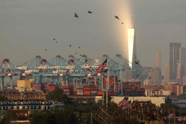Cargo ships and shipping containers are seen at the Port Jersey Container Terminal, with the Manhattan skyline and the One World Trade Center (also known as the Freedom Tower) in the distance, in Jersey City, New Jersey on September 22, 2025. (Photo by CHARLY TRIBALLEAU / AFP)