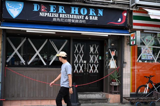 A man walks past a restaurant with taped up windows as Super Typhoon Ragasa approaches Hong Kong on September 23, 2025. Hong Kong rushed to prepare for the arrival of Super Typhoon Ragasa, with officials warning of a "serious threat" comparable to some of the most destructive storms in the city's recent history. (Photo by Peter PARKS / AFP)