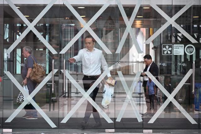 A shopper exits a shopping mall with taped up windows as Super Typhoon Ragasa approaches Hong Kong on September 23, 2025. Hong Kong rushed to prepare for the arrival of Super Typhoon Ragasa, with officials warning of a "serious threat" comparable to some of the most destructive storms in the city's recent history. (Photo by Peter PARKS / AFP)