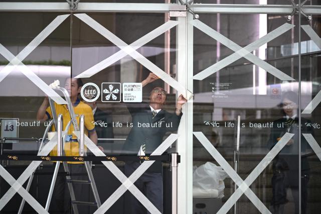 Workers tape up windows in a shopping mall as Super Typhoon Ragasa approaches Hong Kong on September 23, 2025. Hong Kong rushed to prepare for the arrival of Super Typhoon Ragasa, with officials warning of a "serious threat" comparable to some of the most destructive storms in the city's recent history. (Photo by Peter PARKS / AFP)
