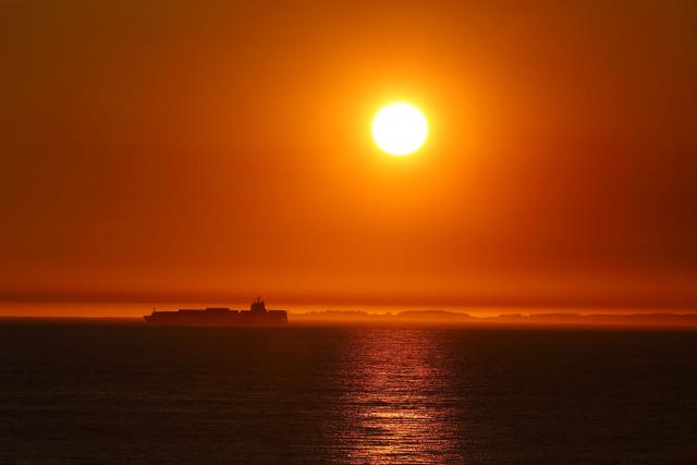 This picture taken on September 22, 2025, shows a container ship moored off Fremantle port as the sun sets in Perth. (Photo by Antony DICKSON / AFP)