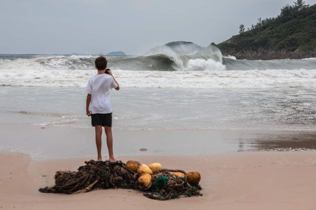 A man watches large waves break at a beach as Super Typhoon Ragasa moved towards Hong Kong on September 23, 2025. Hong Kong shut schools and cancelled flights on September 23 as Super Typhoon Ragasa was set to slam into the financial centre with a force that officials warned would be among the most destructive in the city's recent history. (Photo by Dale DE LA REY / AFP)