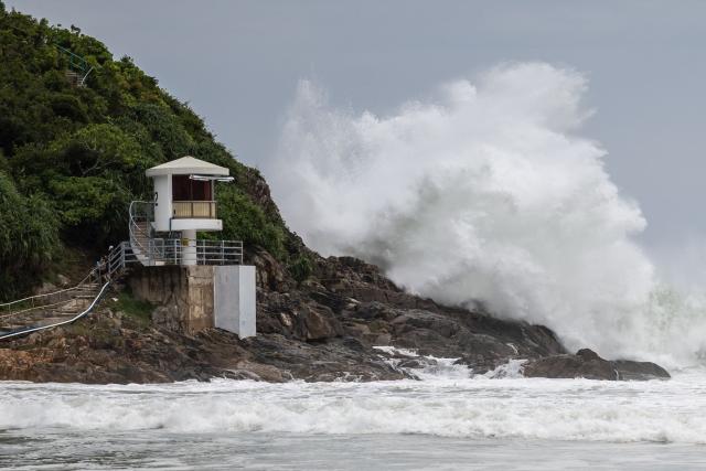 A large waves breaks behind a lifeguard tower at a beach as Super Typhoon Ragasa moved towards Hong Kong on September 23, 2025. Hong Kong shut schools and cancelled flights on September 23 as Super Typhoon Ragasa was set to slam into the financial centre with a force that officials warned would be among the most destructive in the city's recent history. (Photo by Dale DE LA REY / AFP)