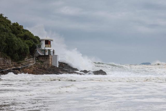 A man watches large waves break at a beach as Super Typhoon Ragasa moved towards Hong Kong on September 23, 2025. Hong Kong shut schools and cancelled flights on September 23 as Super Typhoon Ragasa was set to slam into the financial centre with a force that officials warned would be among the most destructive in the city's recent history. (Photo by Dale DE LA REY / AFP)
