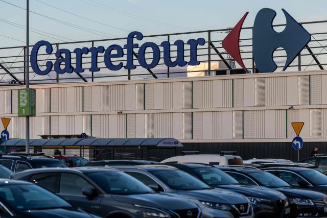 The logo of French supermarket chain Carrefour is lit on the roof of a large-scale store as cars are parked in the suburbs of Warsaw, Poland, on September 23, 2025. (Photo by Wojtek RADWANSKI / AFP)