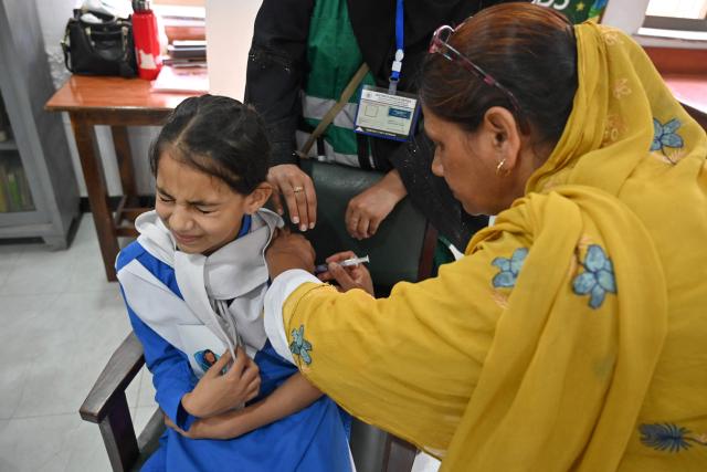 A health worker (R) injects human papillomavirus (HPV) vaccine to a school student in Islamabad on September 24, 2025, during a vaccination drive held to protect adolescent girls from cervical cancer. (Photo by Farooq NAEEM / AFP)