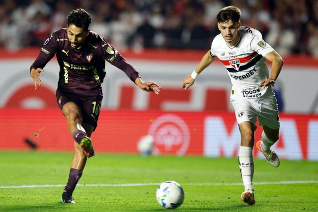 Liga de Quito's Colombian forward #16 Jeison Medina (L) shoots and scores his team's first goal past Sao Paulo's Paraguayan midfielder #21 Damian Bobadilla (R) during the Copa Libertadores quarterfinal second leg football match between Brazil's Sao Paulo and Ecuador's Liga de Quito, at the Morumbi stadium in Sao Paulo, Brazil on September 25, 2025. (Photo by Miguel SCHINCARIOL / AFP)