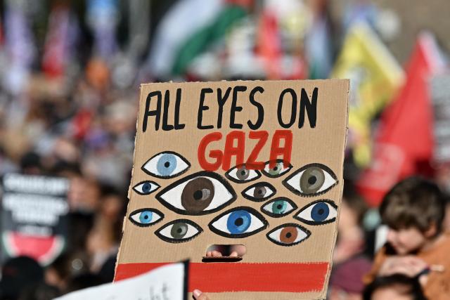 A participant displays a placard with the lettering 'All Eyes on Gaza' as people march during a demonstration under the motto 'Draw the red line with us: Together for Gaza!' in Berlin on September 27, 2025. (Photo by RALF HIRSCHBERGER / AFP)