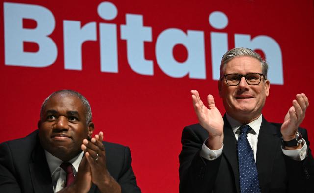 Britain's Prime Minister Keir Starmer (R) and Britain's Justice Secretary and deputy Prime Minister David Lammy applaud as they attend the first day of the annual Labour Party conference in Liverpool, north-west England, on September 28, 2025. Britain's ruling Labour party began to gather for its annual meeting on Sunday, with underfire Prime Minister Keir Starmer battling to convince nervous lawmakers that he is the right leader to fend off soaring support for the hard right. (Photo by Paul ELLIS / AFP)