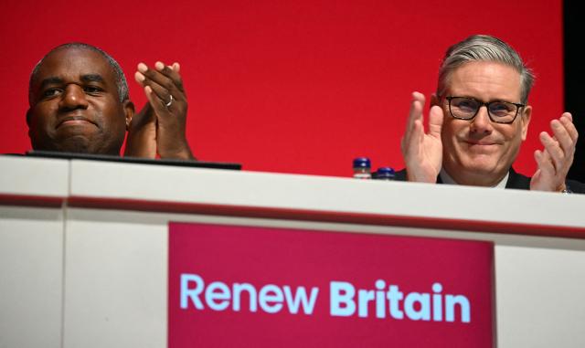 Britain's Prime Minister Keir Starmer (R) and Britain's Justice Secretary and deputy Prime Minister David Lammy applaud as they attend the first day of the annual Labour Party conference in Liverpool, north-west England, on September 28, 2025. Britain's ruling Labour party began to gather for its annual meeting on Sunday, with underfire Prime Minister Keir Starmer battling to convince nervous lawmakers that he is the right leader to fend off soaring support for the hard right. (Photo by Paul ELLIS / AFP)