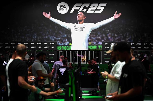 (FILES) Visitors play the 'EA Sports FC 25' game in front of a placard with England's midfielder Jude Bellingham at the Electronic Arts booth during the media day at the Gamescom video games trade fair in Cologne, western Germany on August 21, 2024. Video game giant Electronic Arts announced on September 29, 2025, it would be acquired by a consortium led by Saudi Arabia's Public Investment Fund for $55 billion, in what EA said would be the largest all-cash private equity buyout in history. (Photo by Ina FASSBENDER / AFP)