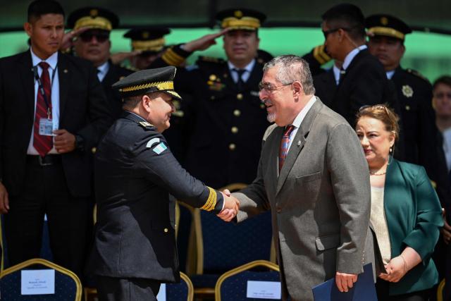 Guatemalan President Bernardo Arevalo (R) shakes hands with Director of the National Civil Police David Boteo during the graduation ceremony of 3,228 policemen at the Cementos Progreso Stadium in Guatemala City on September 29, 2025. (Photo by Johan ORDONEZ / AFP)