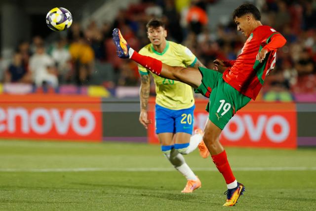 Morocco's defender #19 Smail Bakhty kicks the ball next to Brazil's midfielder #20 Erick Bele during the 2025 FIFA U-20 World Cup football match between Brazil and Morocco at the National Stadium in Santiago on October 1, 2025. (Photo by Raul BRAVO / AFP)