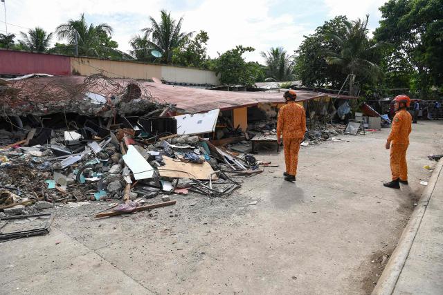 Bureau of Fire Protection personnel inspect a collapsed building inside a housing project for Super Typhoon Haiyan survivors in Bogo City, Cebu province on October 2, 2025, in the aftermath of a 6.9-magnitude quake that struck off the coast of the central Philippines late September 30. (Photo by Ted ALJIBE / AFP)