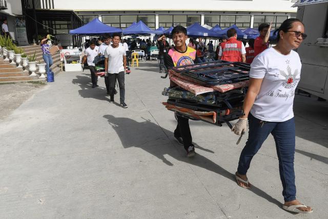People carry folding beds outside the provincial hospital  in Bogo City, Cebu province on October 2, 2025, in the aftermath of a 6.9-magnitude quake that struck off the coast of the central Philippines late September 30. The death toll from a powerful earthquake in the central Philippines rose to 72 on October 2, rescuers said, as officials turned their efforts to the hundreds injured and thousands left homeless. (Photo by Ted ALJIBE / AFP)