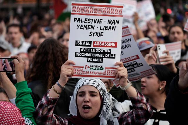 A participant holds a placard reading "Israel murders with France's total support" during a demonstration in solidarity with Palestinians and to condemn the interception of the Global Sumud Flotilla by Israeli army, at Place de la Republique in Paris, on October 2, 2025. Israel said on October 2 it will deport pro-Palestinian activists aboard the intercepted Sumud Flotilla of around 45 vessels, which began its voyage a month earlier, with politicians and activists aiming to break the siege and deliver aid to Gaza, where a famine was declared by the United Nations. (Photo by STEPHANE DE SAKUTIN / AFP)