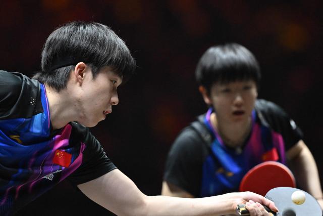 China’s Wang Chuqin (L) hits a return next to Sun Yingsha (R) to Brazil’s Hugo Calderano and Bruna Takahashi during their mixed doubles semi-final match at the China Smash Table Tennis tournament in Beijing on October 2, 2025. (Photo by ADEK BERRY / AFP)