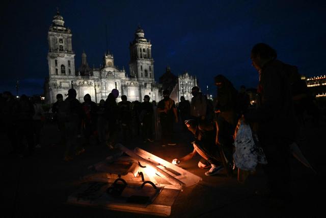Demonstrators burn riot police shoieds during a rally commemorating the 57th anniversary of the 1968 Tlatelolco student massacre at the Zocalo Square in Mexico City on October 2, 2025. (Photo by Yuri CORTEZ / AFP)